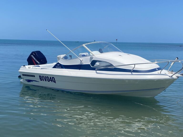 A White and Blue Motor Boat Floating on The Ocean — Secondhand Boat Motors in Hervey Bay
